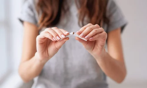 Stop smoking cigarettes concept. Portrait of beautiful smiling girl holding broken cigarette in hands. Happy female quitting smoking cigarettes. Quit bad habit, health care concept. No smoking.