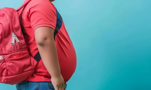 Overweight schoolboy with red backpack against blue background